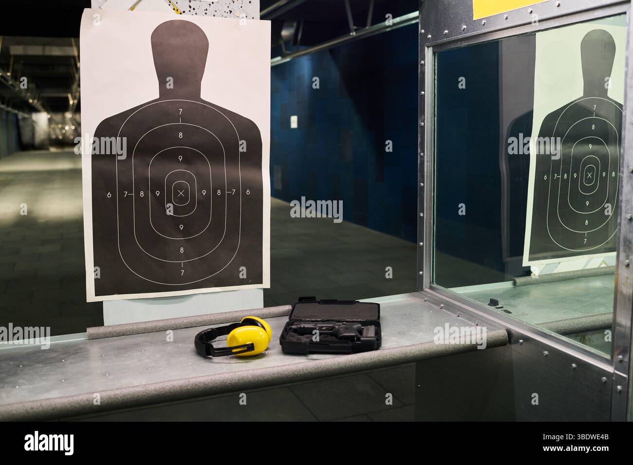 Indoor shooting range showing a silhouette target with a gun and ear ...