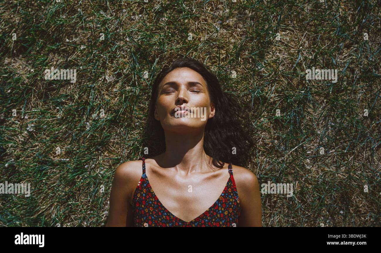 Serene woman relaxing and lying on a grass Stock Photo
