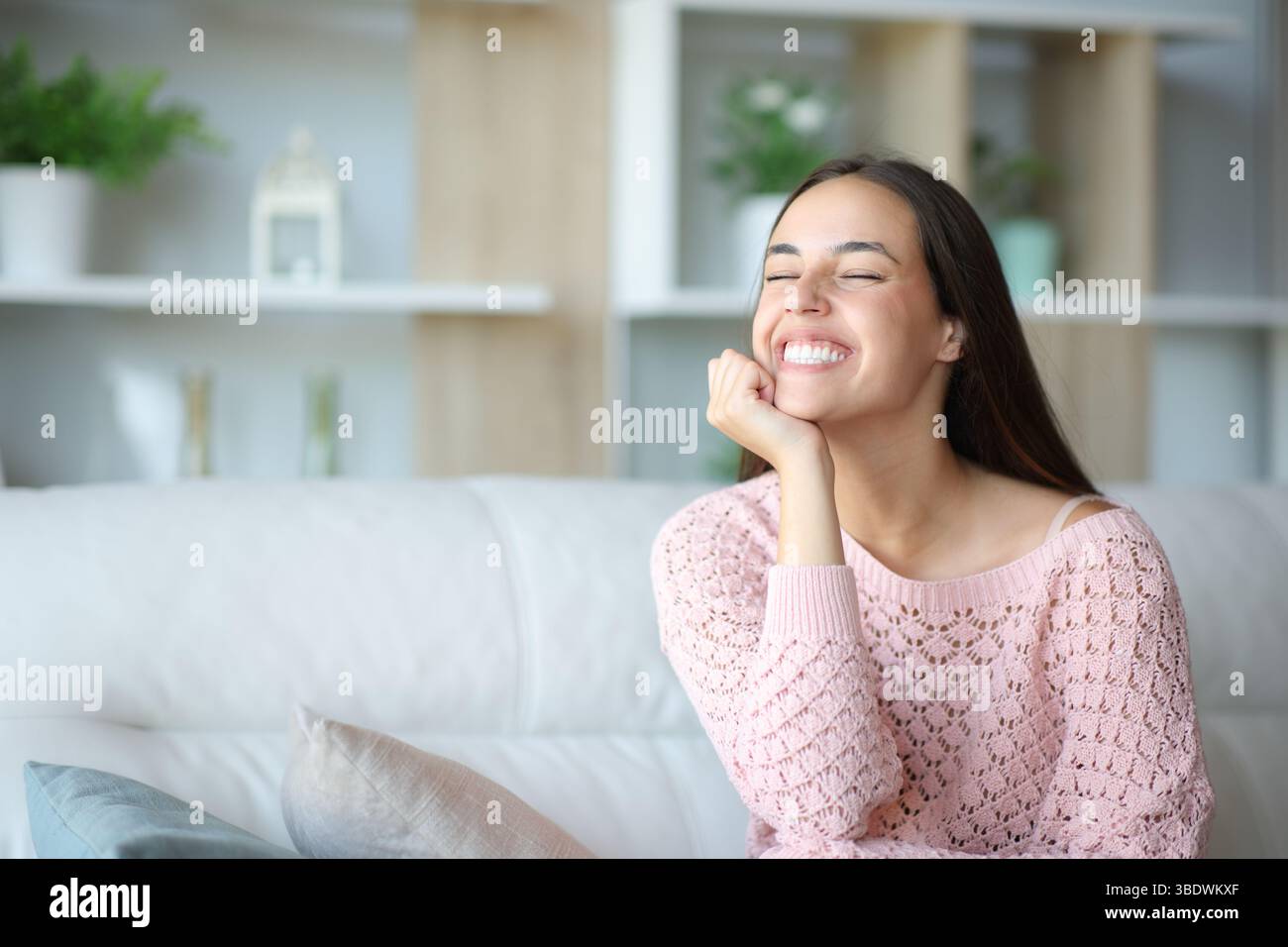 Happy woman sitting on a couch at home relaxing Stock Photo