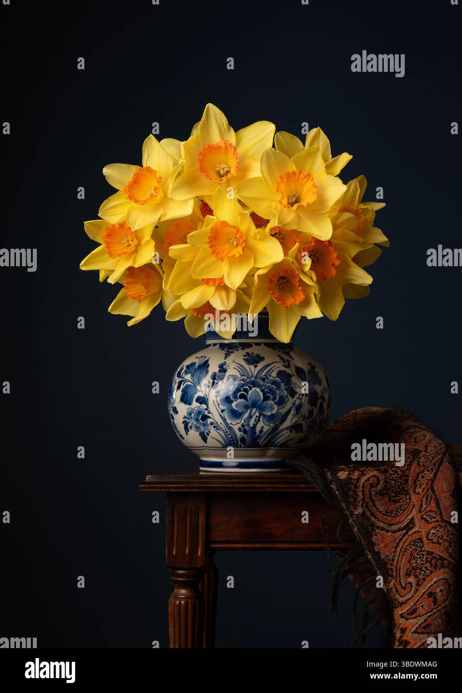 Still life with a bouquet of daffodil flowers in a delft blue vase on a ...