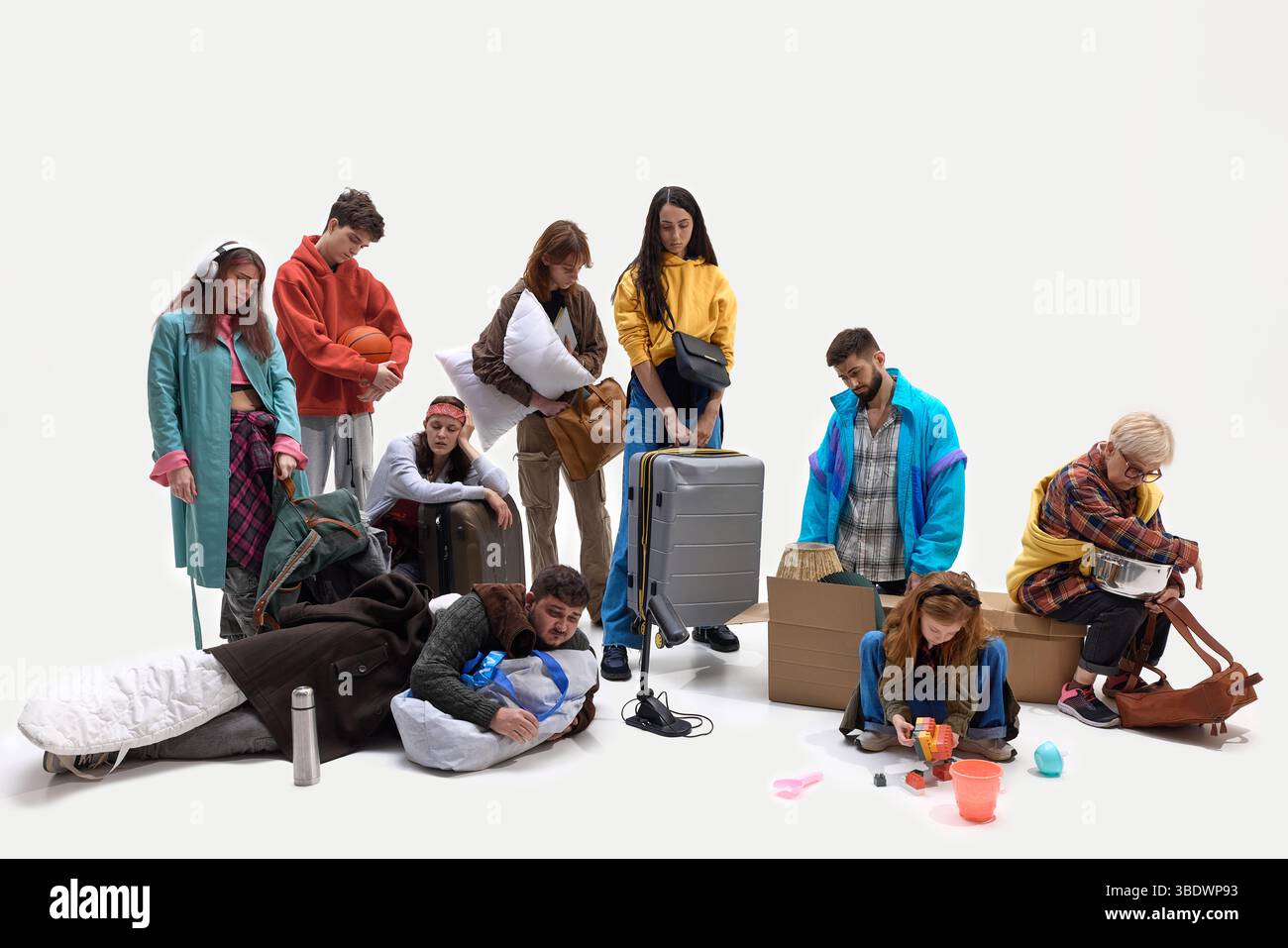 People collapse on floor surrounded by personal belongings after long journey or displacement. Concept of evacuation, refugee experience, social Stock Photo