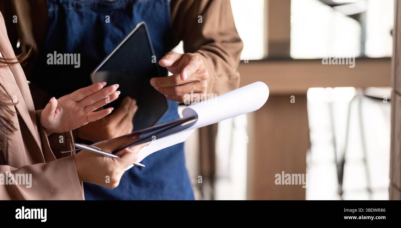 Collaborative Business Discussion. Two professionals engaging in a productive meeting over a tablet and documents. Stock Photo