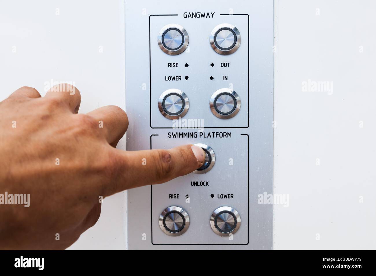 Man's hand pushing the control button of a platform for diving from a yacht. Stock Photo