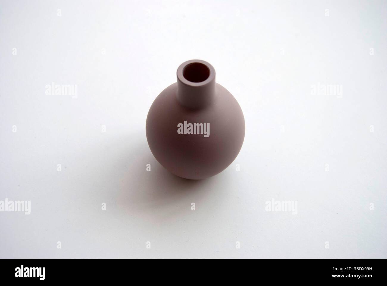 A small clay pot isolated on a white background. A tiny brown vase. Stock Photo