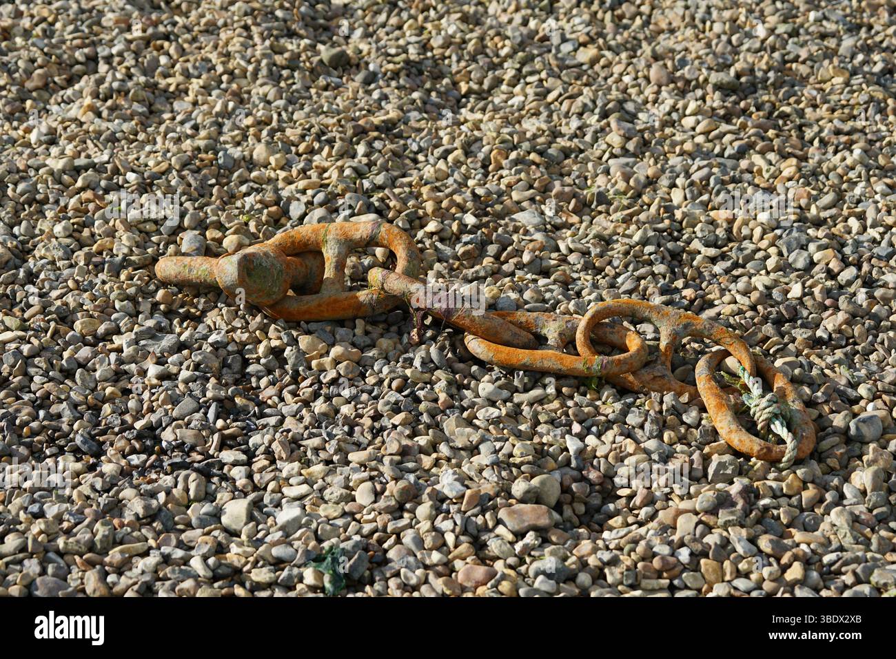 Rusty Chain Lying on Gravel Surface Highlighting Decay and Time Passage. Itchenor, UK Stock Photo