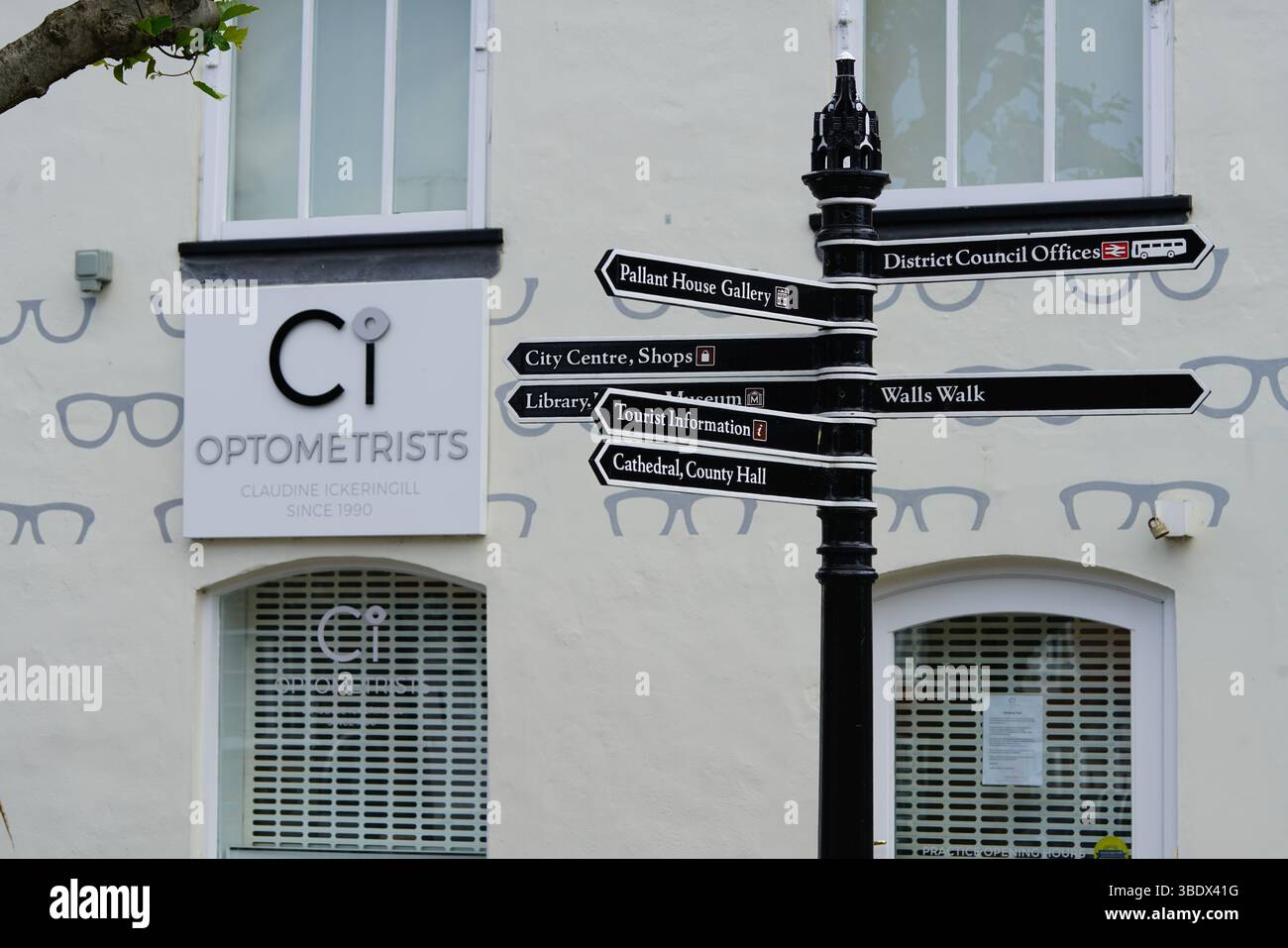 Street Direction Signpost and Optometrist Shop in Urban Setting. Chichester, UK Stock Photo