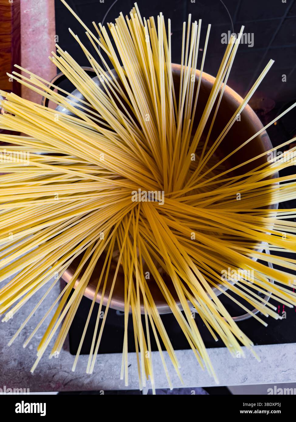 The first stage in cooking spaghetti  - fanning out the sticks in the pot Stock Photo