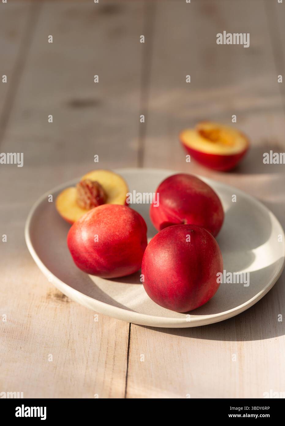 Fresh, ripe nectarines on a plate on a wooden table Stock Photo