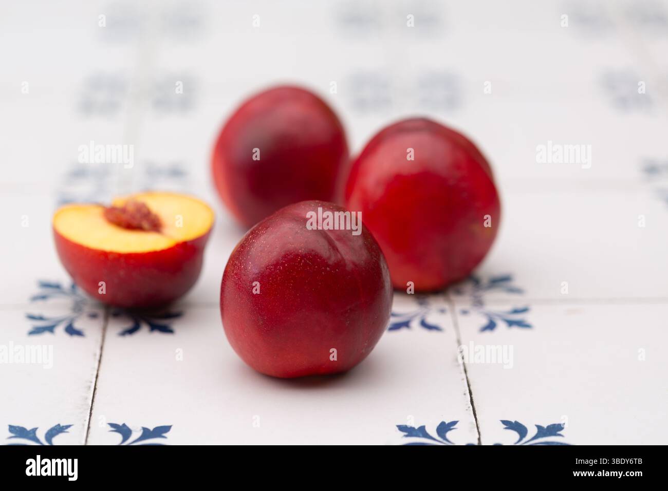 Shiny, ripe nectarines on white and blue tiles Stock Photo