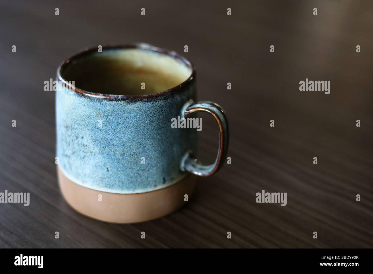 Beautiful handmade, turquoise ceramic mug on the dark wood table Stock Photo