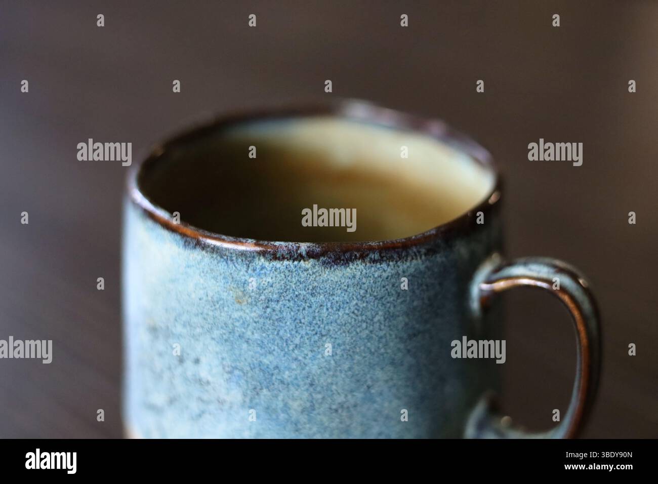 Beautiful handmade, turquoise ceramic mug on the dark wood table Stock Photo
