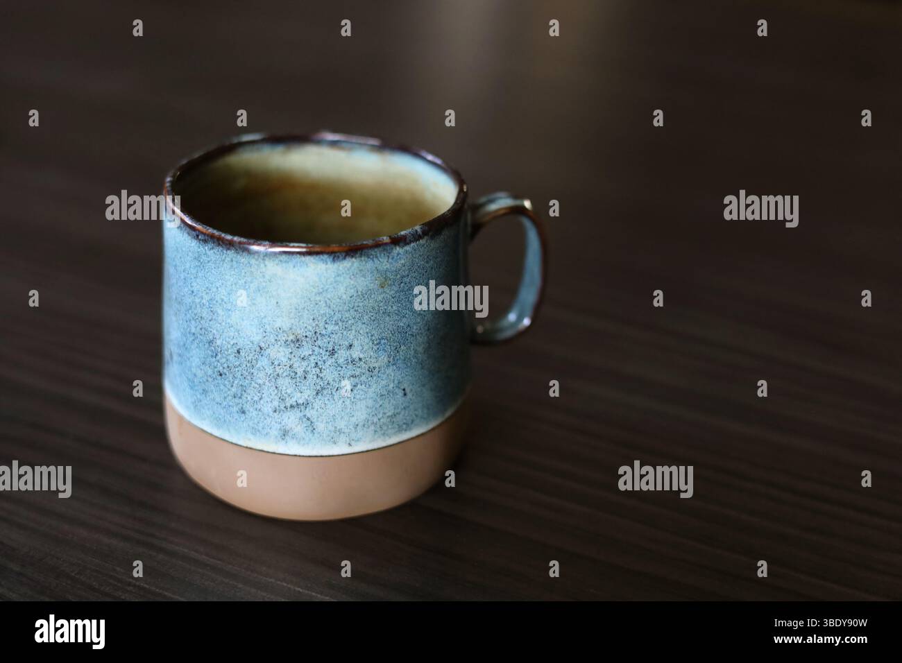 Beautiful handmade, turquoise ceramic mug on the dark wood table Stock Photo