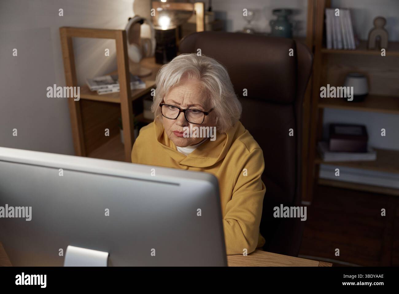 Focused elderly woman using desktop computer at home portrait shot Stock Photo