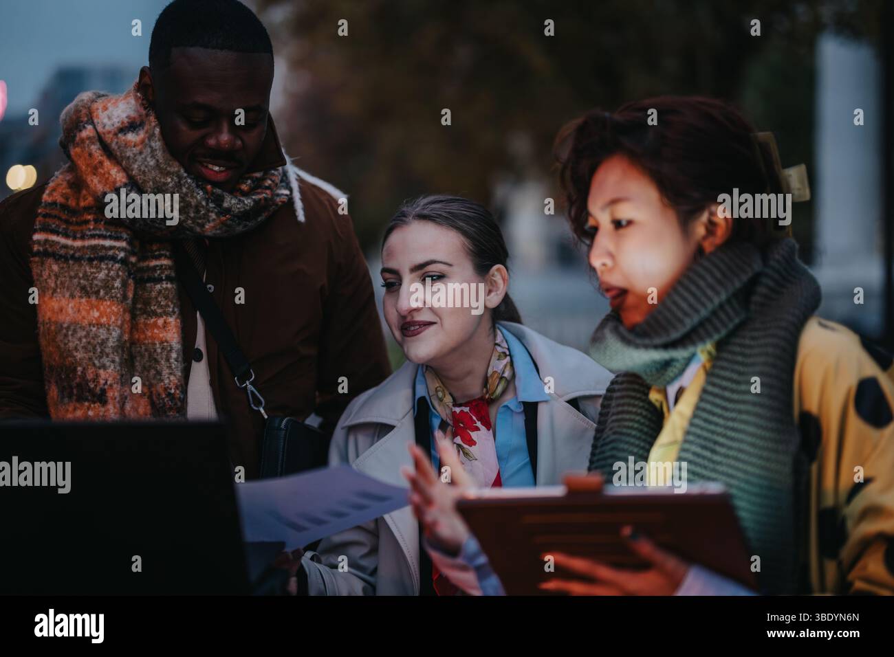 Multiracial team collaborating outdoors in a modern urban setting during the evening Stock Photo
