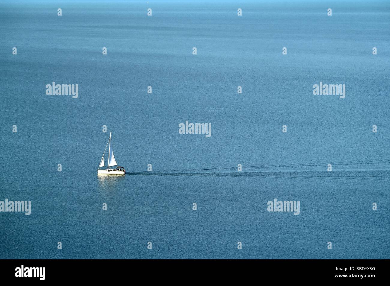 Sailboat with white sail on calm blue water in springtime viewed from Tihany, Lake Balaton, Hungary Stock Photo