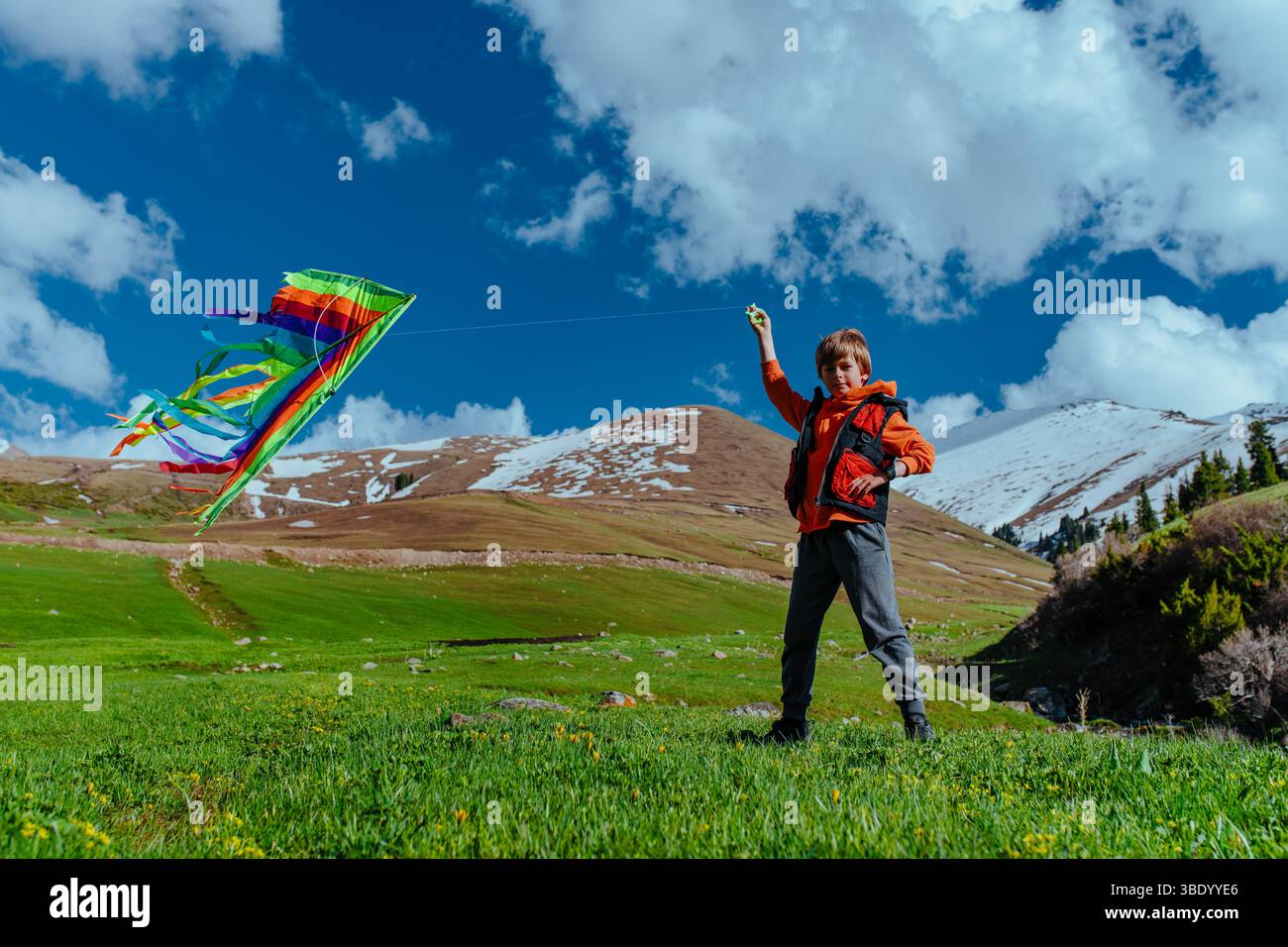 Boy hiker with kite on mountains background Stock Photo