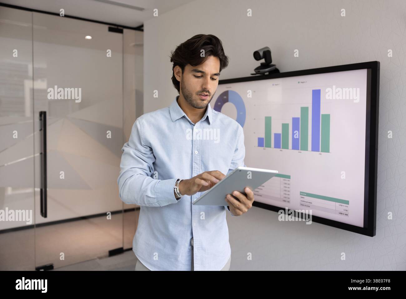 Focused Hispanic businessman working in office using tablet Stock Photo