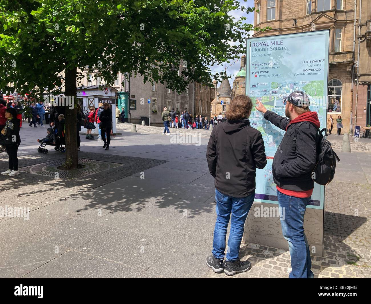 Visitors at information board with city map and attractions on Hunter Square and Royal Mile, Edinburgh Scotland - Smartphone Captured Stock Image