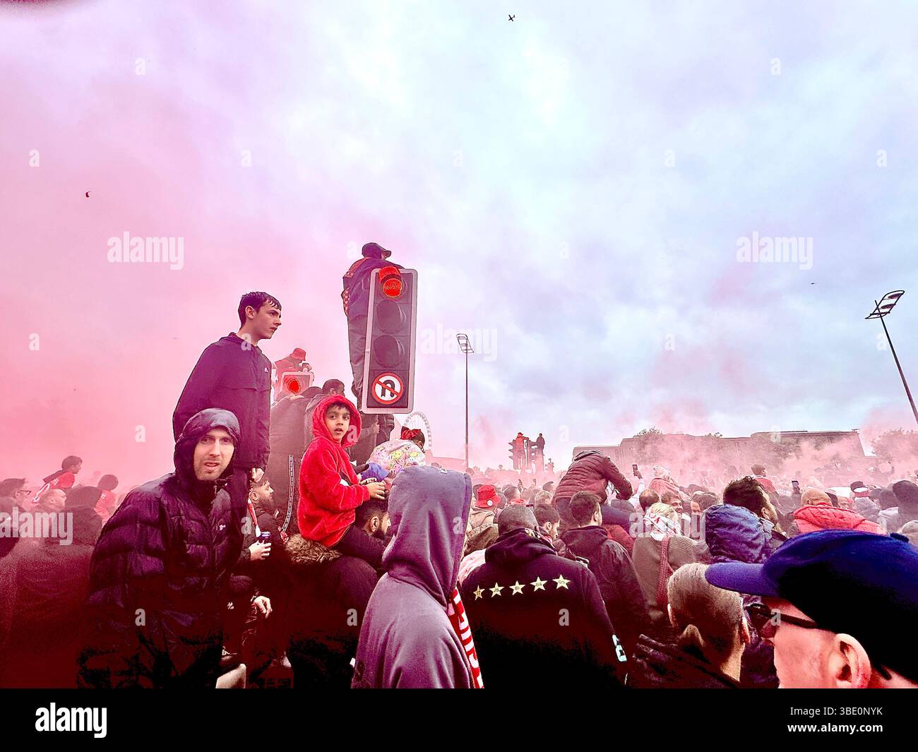 Crowds pack The Strand as red smoke swirls and fans cheer and film the Liverpool victory parade. Strand Street, Liverpool, UK, 26 May 2025. - Smartphone Captured Stock Image