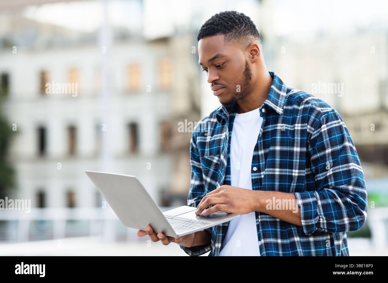 Black man using laptop, standing in city Stock Photo
