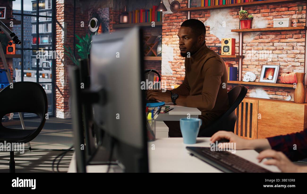 Irked man punching startup office desk in frustration struggling to fix application errors. Upset programmer annoyed by computer bugs while coding in software development agency, camera A Stock Photo