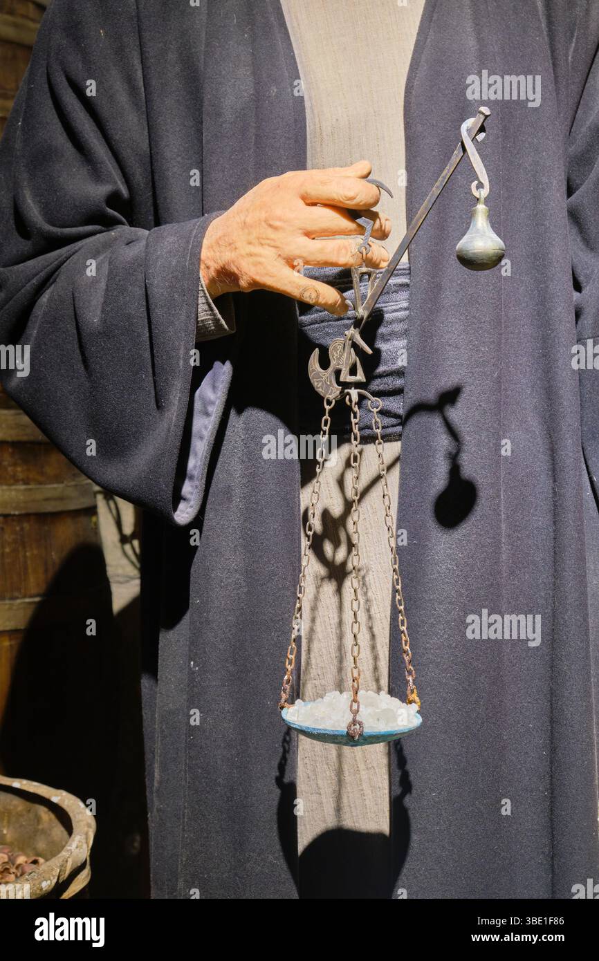An old man merchant using a hand scale for a buyer at his stall at a ...