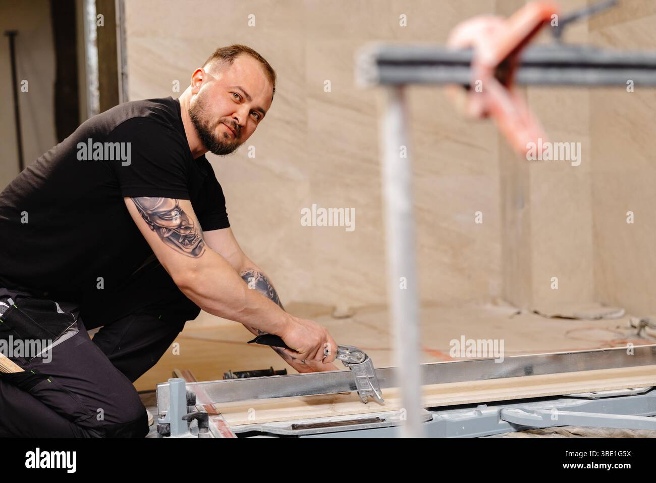 Construction worker cutting ceramic tile using tile cutter while working on bathroom renovation Stock Photo
