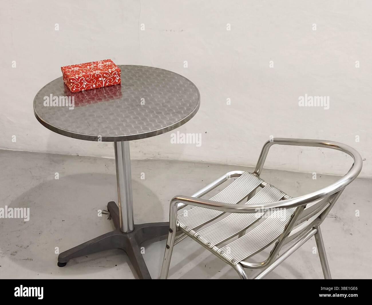 A gift box on a round table with empty chairs in a room Stock Photo