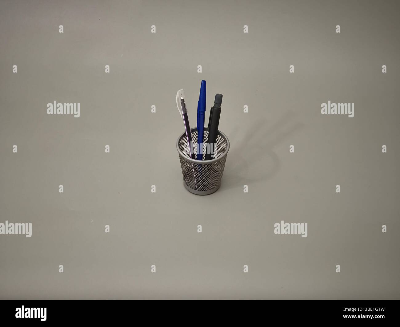 Pencils and pens in a container on a grey background Stock Photo