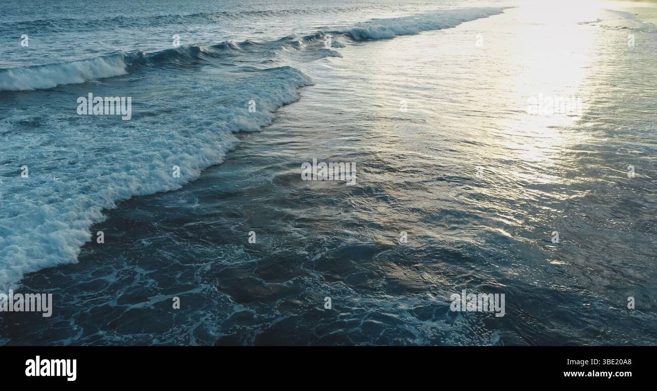Golden hour sunlight reflecting on the rippling ocean water surface ...