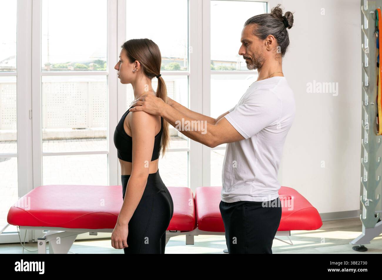 Physiotherapist examining posture of female patient in clinic Stock Photo