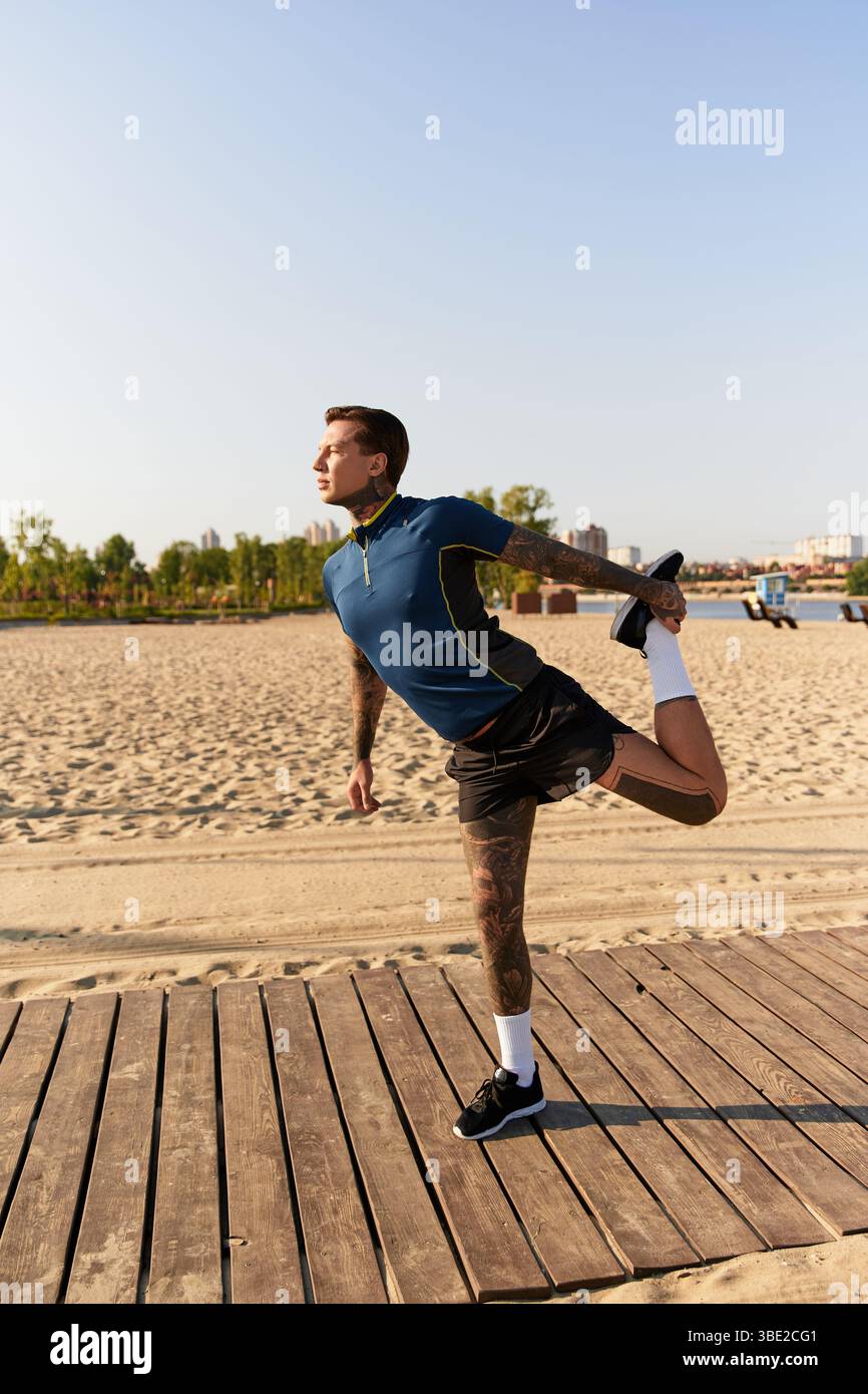 Handsome young man stretches his body on a warm sunny day by the beach ...