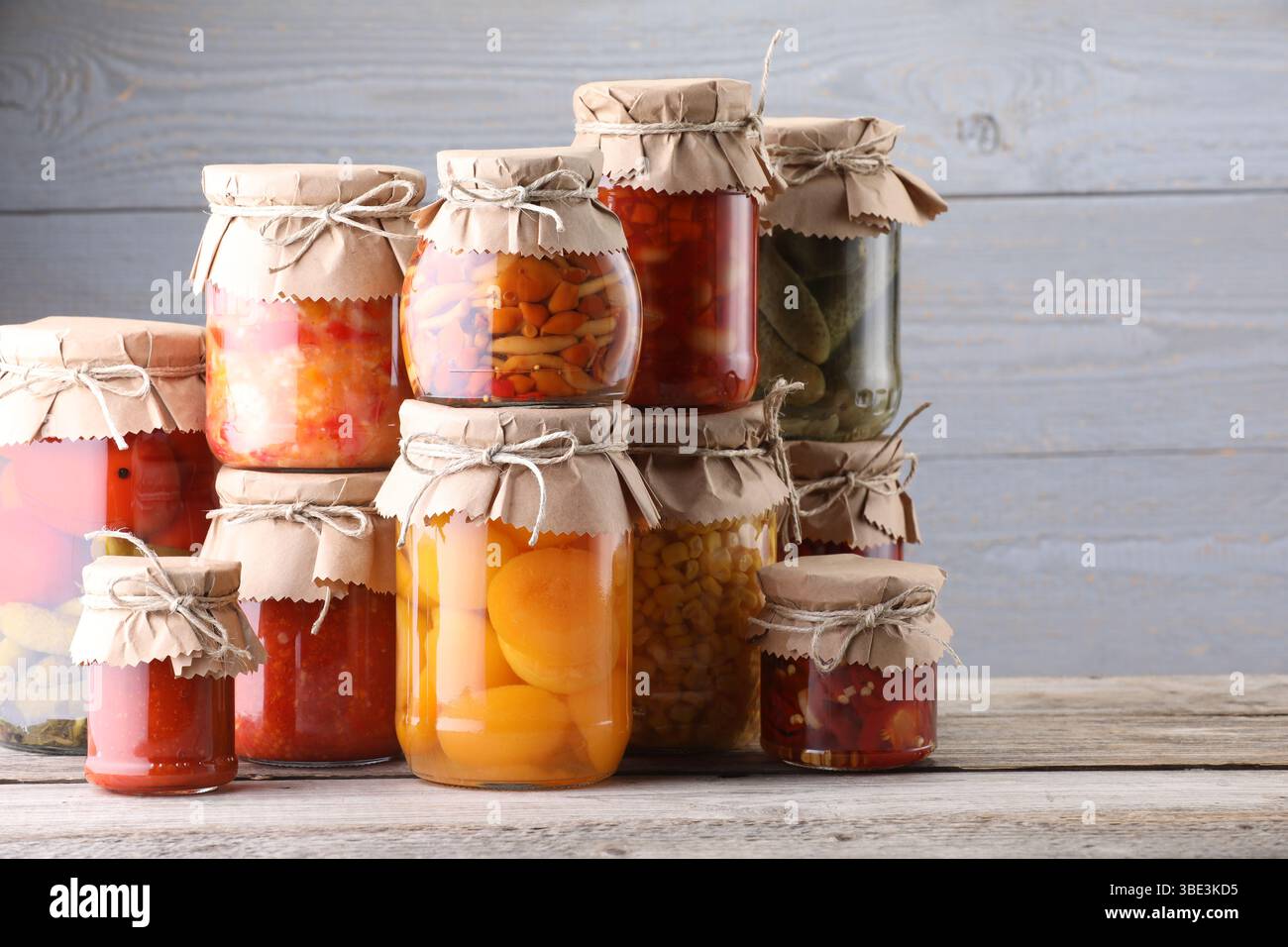 Many jars with different pickled products on wooden table Stock Photo