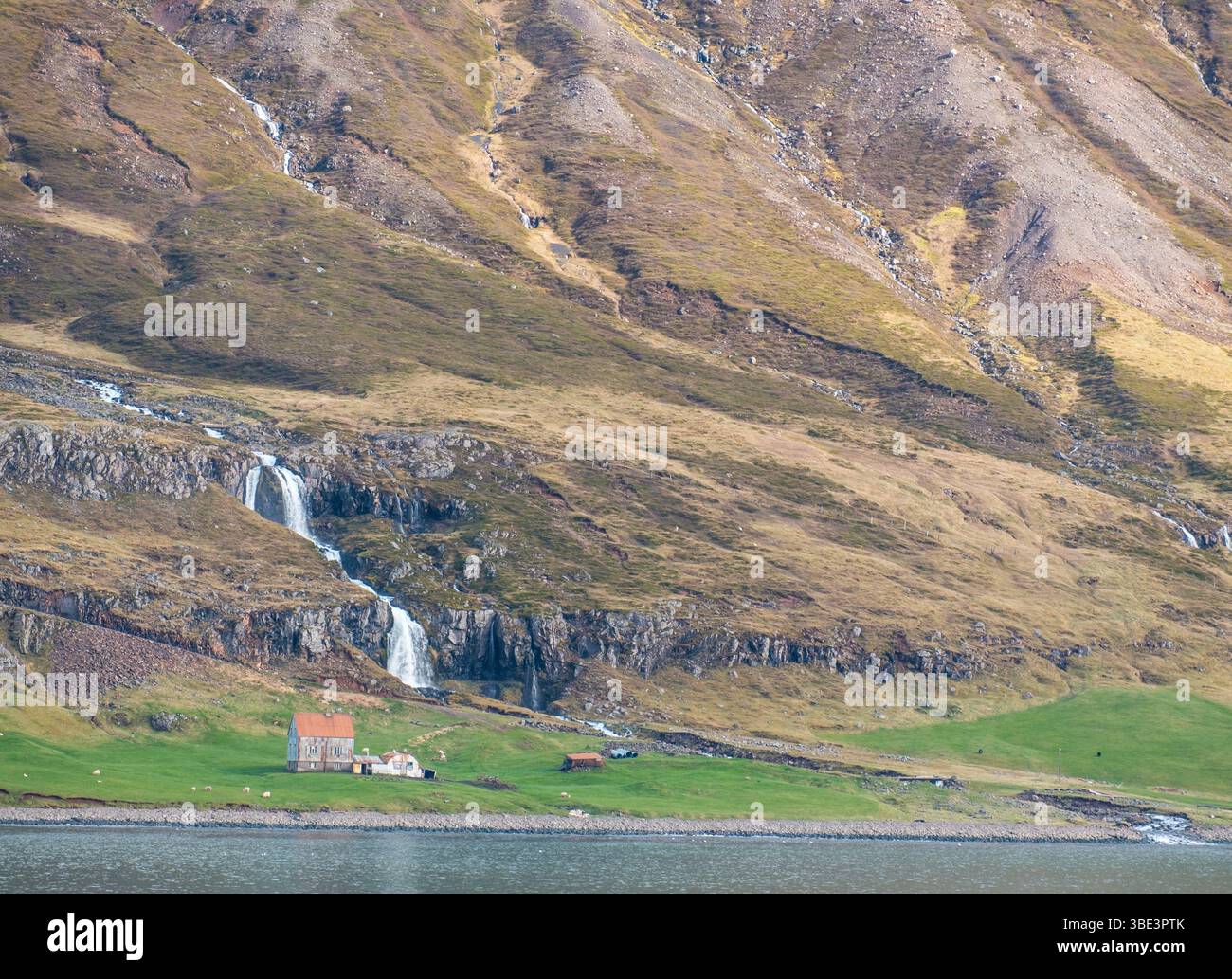 Rural house and cascading waterfall on the coast of Seydisfjordur, East ...