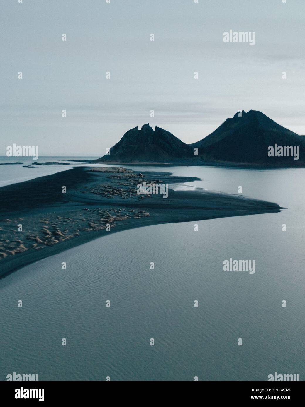 Moody aerial view of Brunnhorn mountain reflected in calm sea, East Iceland. Stock Photo