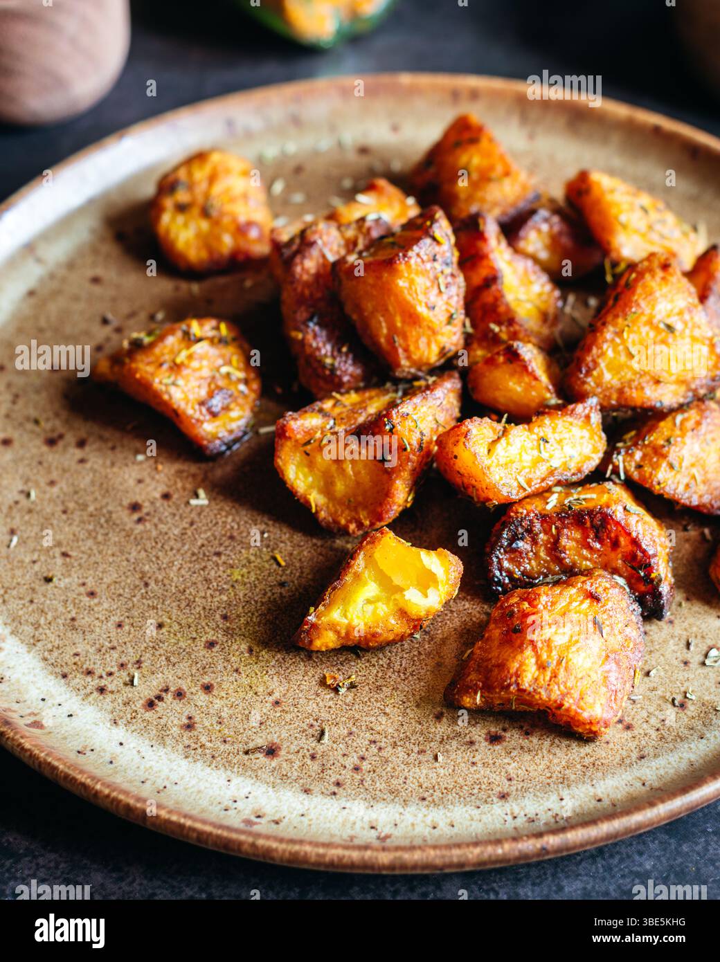 Golden brown roasted potatoes, seasoned with a blend of herbs, arranged ...