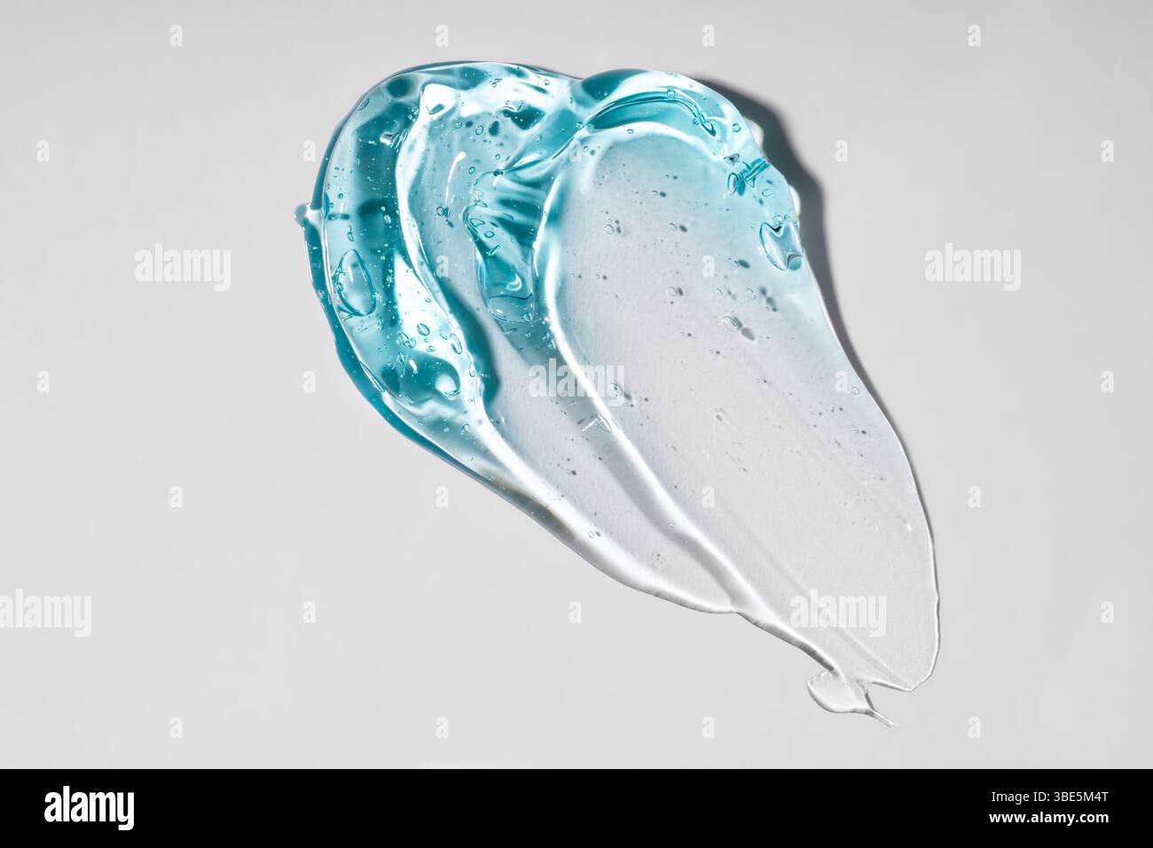 A close-up image of a translucent blue gel texture on a plain, light background. The smooth, flowing pattern highlights the unique, glossy appearance Stock Photo