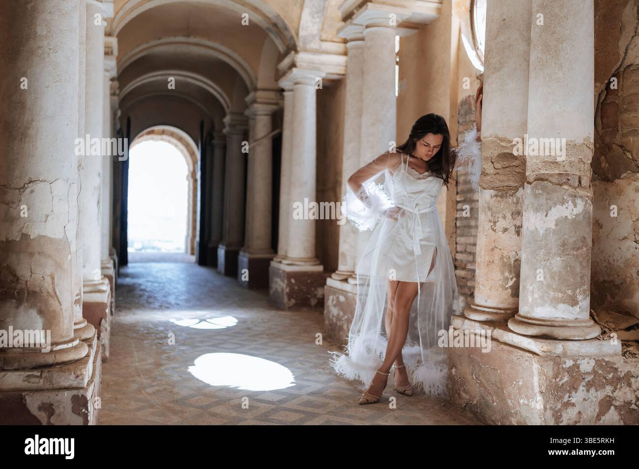 A bride poses elegantly in a flowing white gown amidst the historic architecture of an ancient villa, capturing the romance and charm of a wedding in Stock Photo