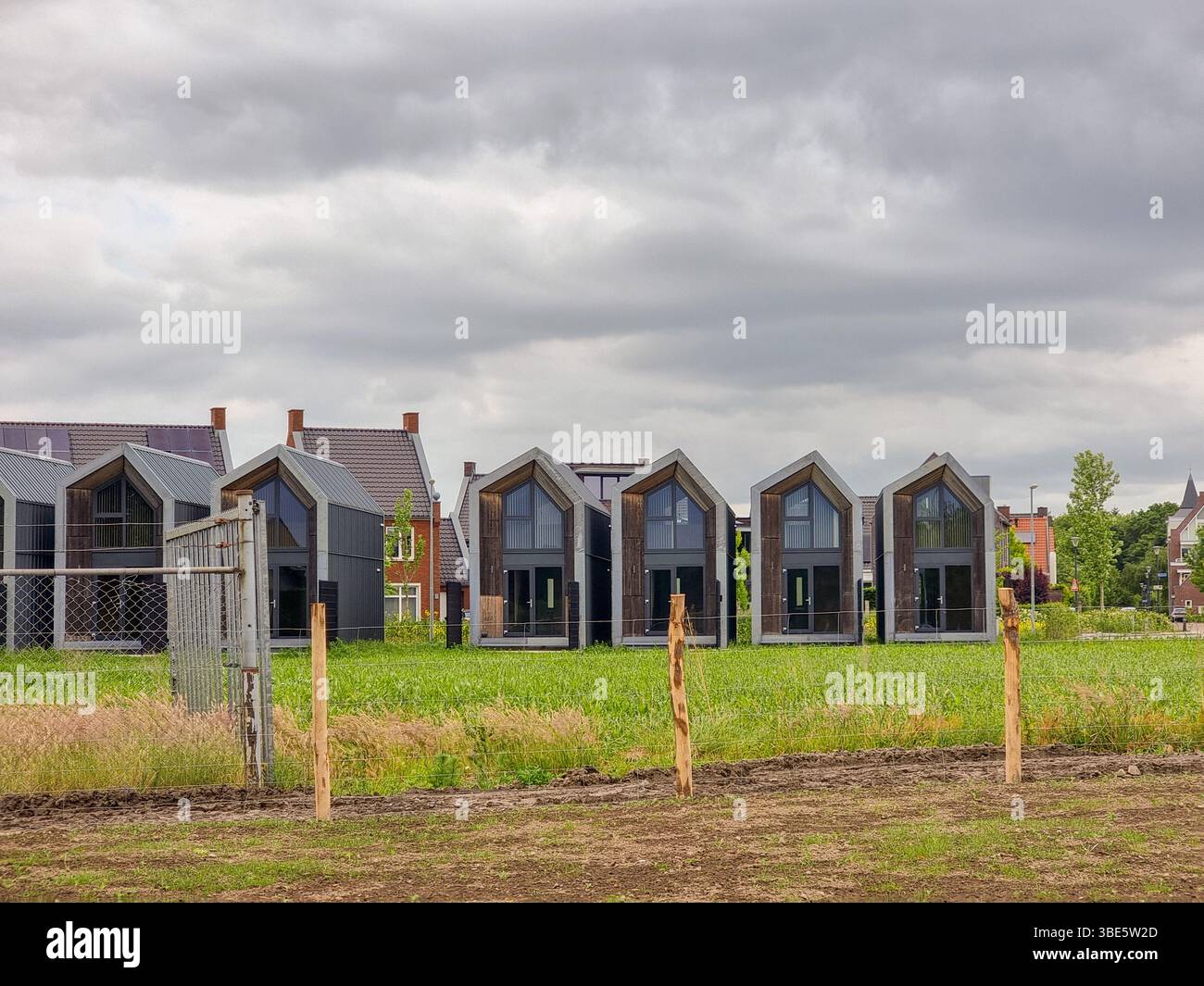 A row of small Tiny Houses behind a green grass field in the Netherlands, Europe - Smartphone Captured Stock Image