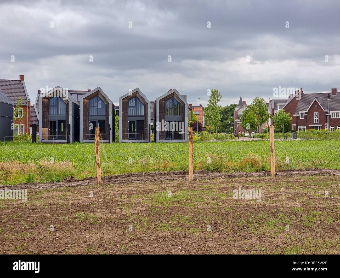 A row of small Tiny Houses behind a green grass field in the Netherlands, Europe - Smartphone Captured Stock Image