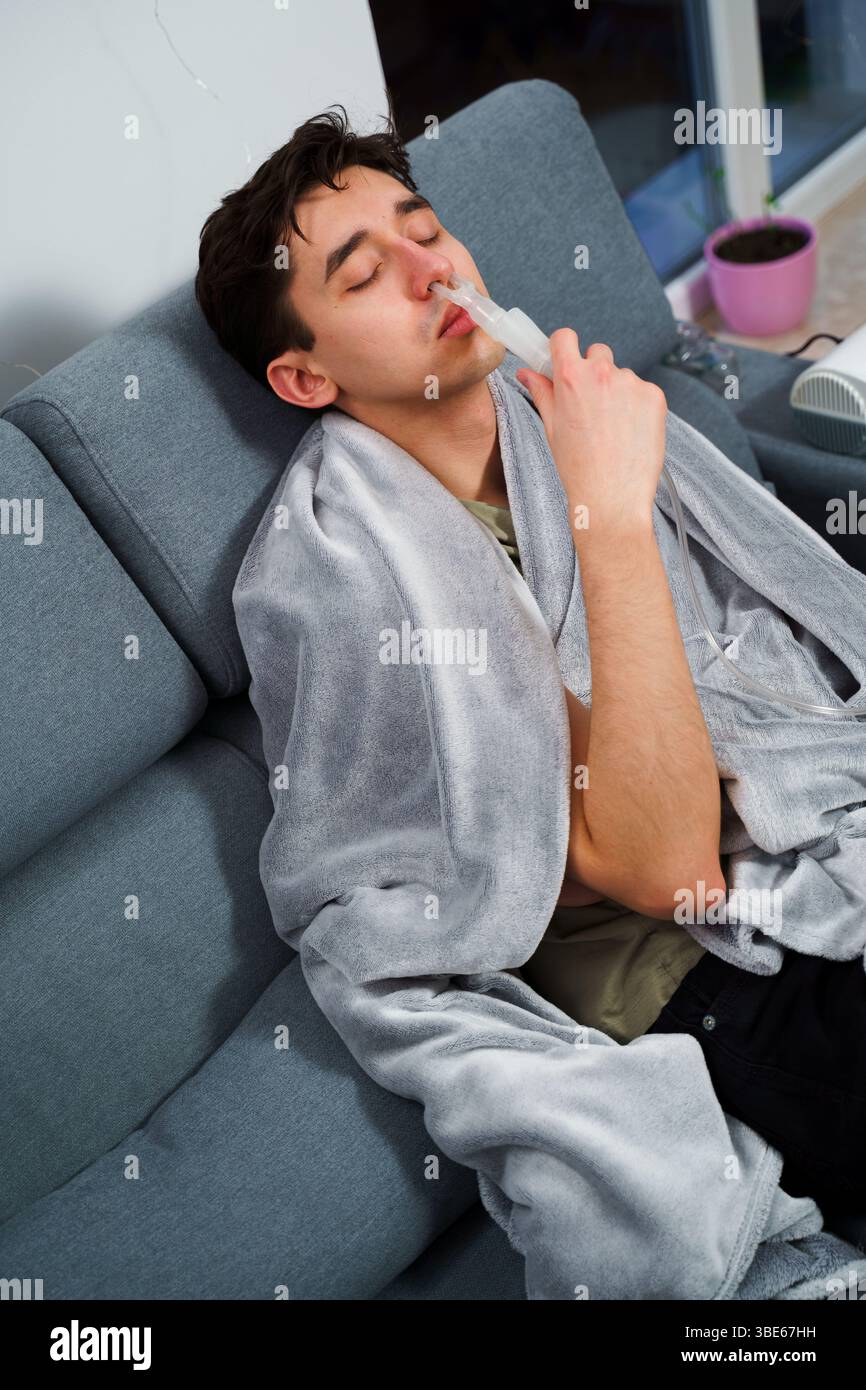 Young man with asthma attack breathing with inhaler in the bad. Doing ...