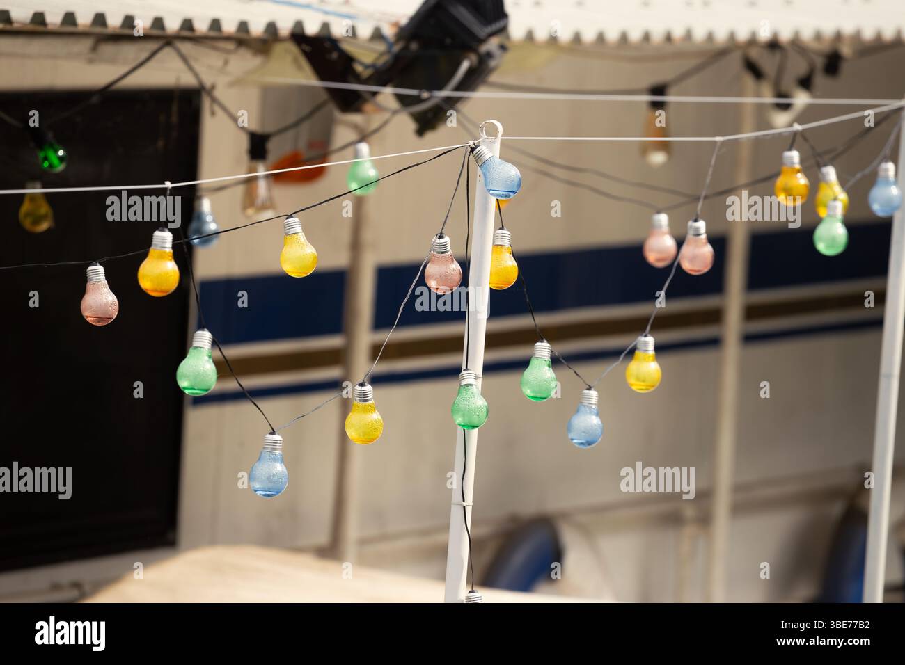 Colorful String Bulbs Hanging Against Outdoor Backdrop Stock Photo
