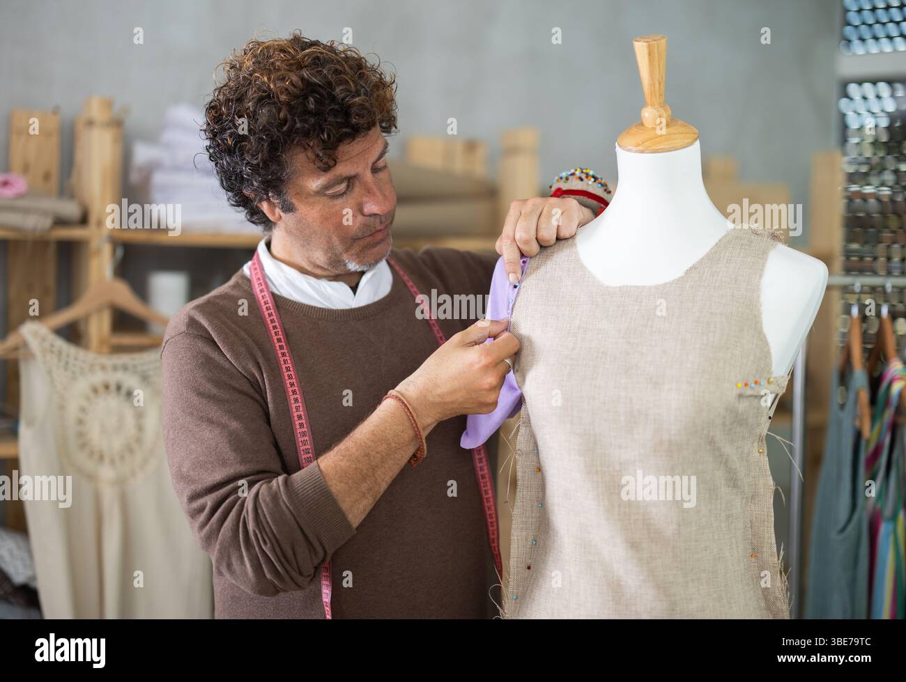 Male tailor standing near mannequin and checking sample quality Stock ...