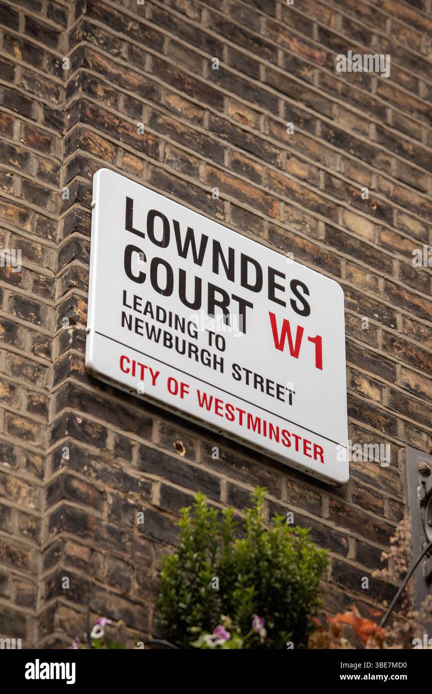 Close-up of a street sign on Lowndes Court in Westminster, London. Brick wall and greenery add texture. Stock Photo