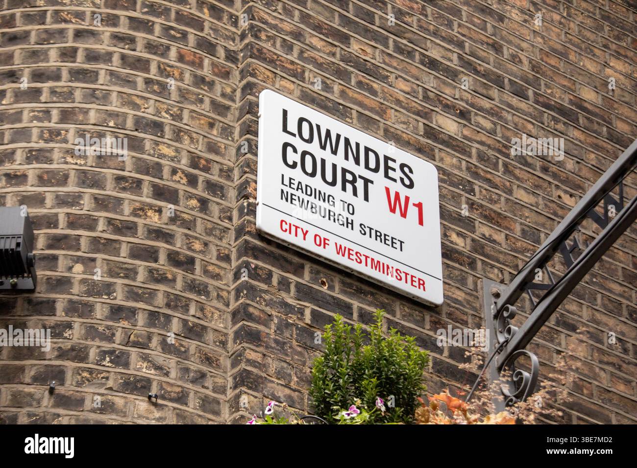 Sign for Lowndes Court leading to Newburgh Street in Westminster, London. Features classic brick wall background. Stock Photo
