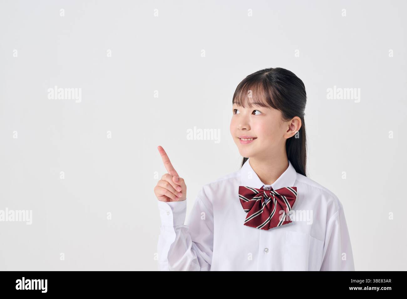 Japanese junior high school girl pointing to the left, white background ...