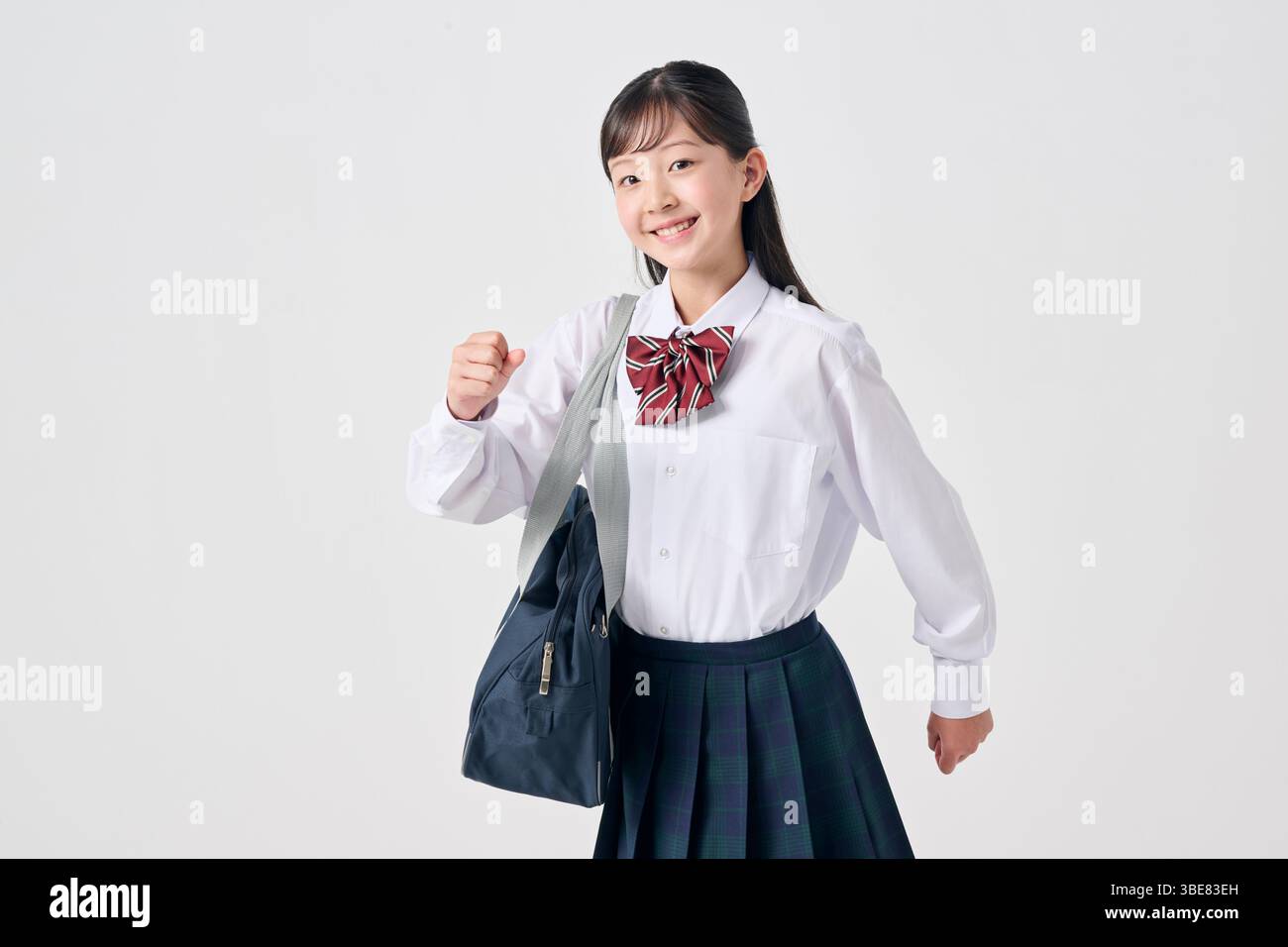 Japanese junior high school girl walking away with schoolbag, white background Stock Photo