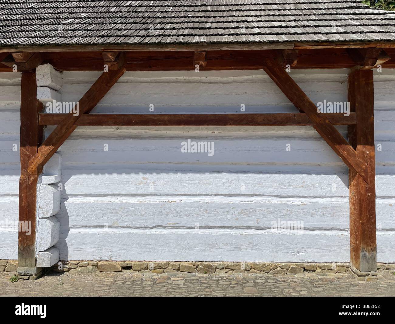 A wooden structure with a white wall and a slanted roof. The structure ...