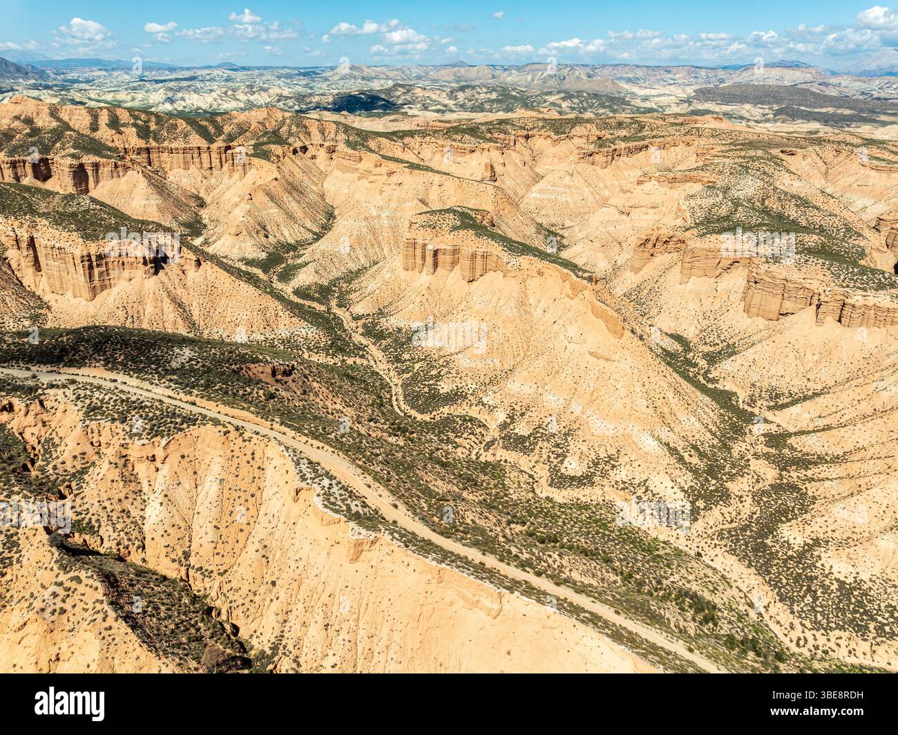 Winding gravel road on a plateau, surrounded by colorful canyons and gorges, aerial view, Gorafe Desert, UNESCO Granada Geopark, Granada province, And Stock Photo