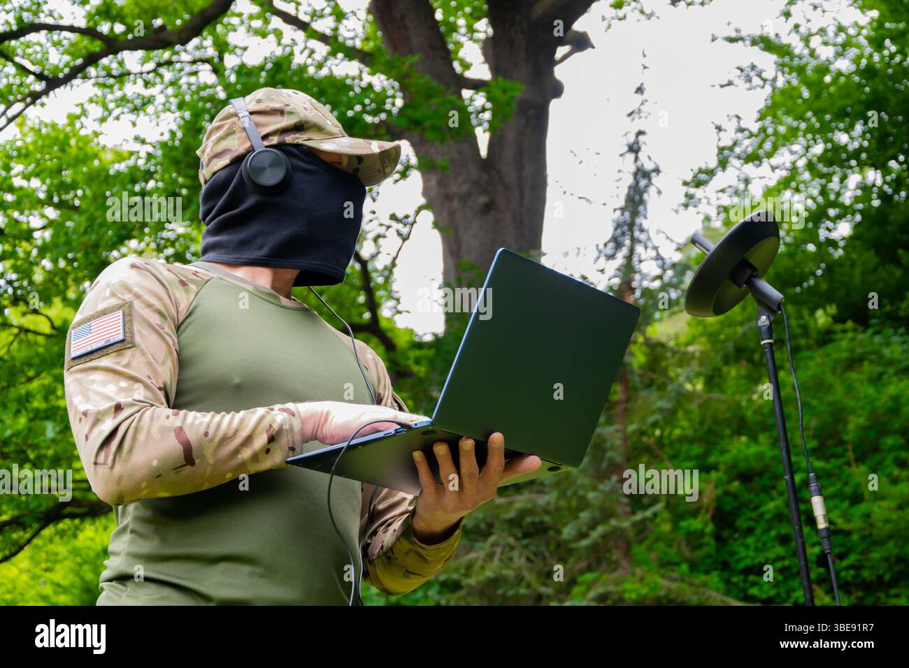 A scout with a laptop and listening equipment works in the wilderness Stock Photo